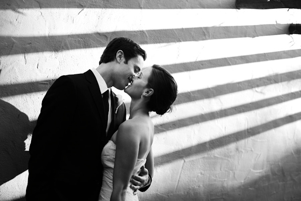 black and white photo of bride and groom kissing with the sunlight coming through the window on them - wedding photo by Jennifer Bowen Photography